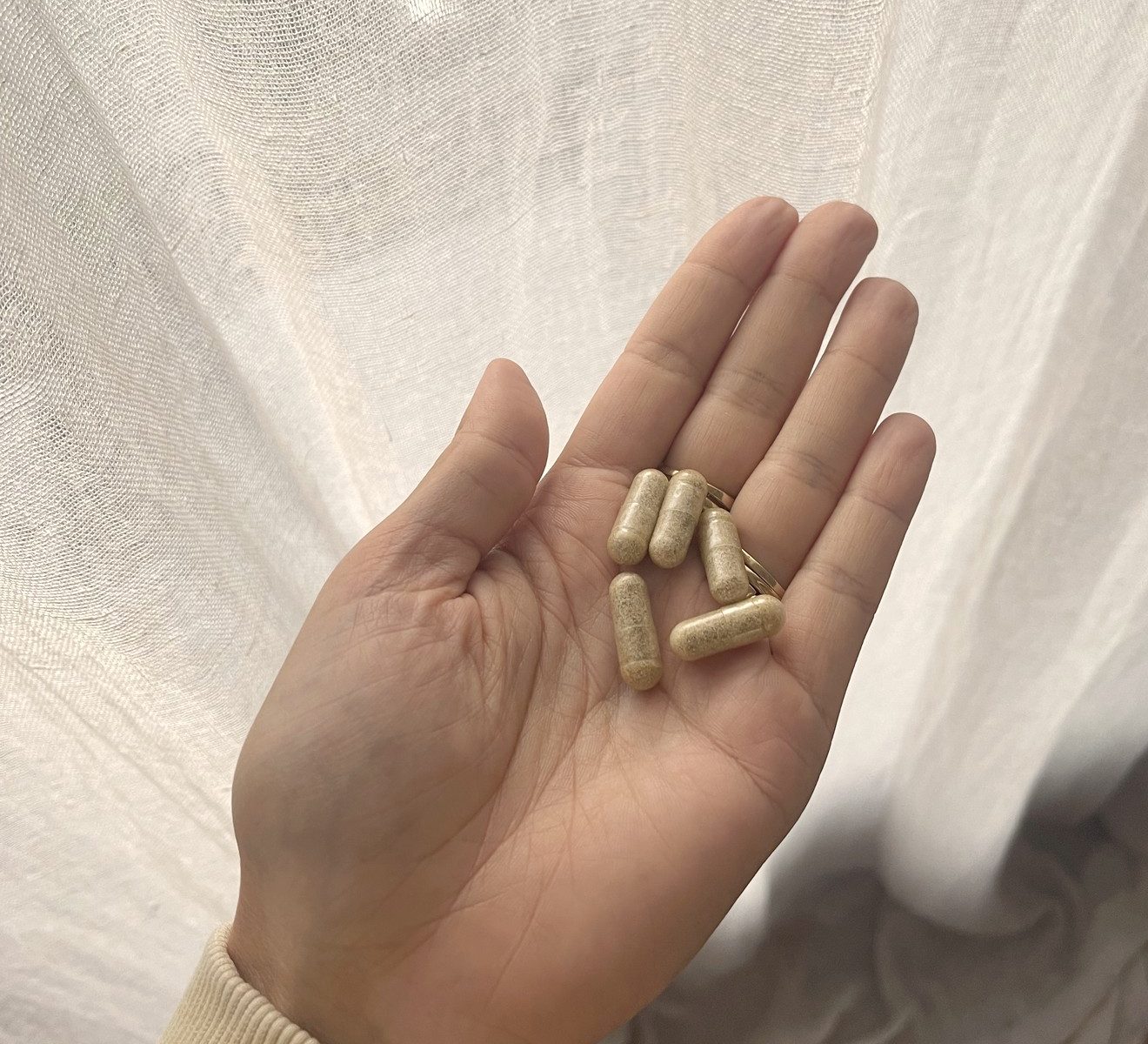 Hand met vijf Cloudless Clear+-capsules voor een licht linnen gordijn